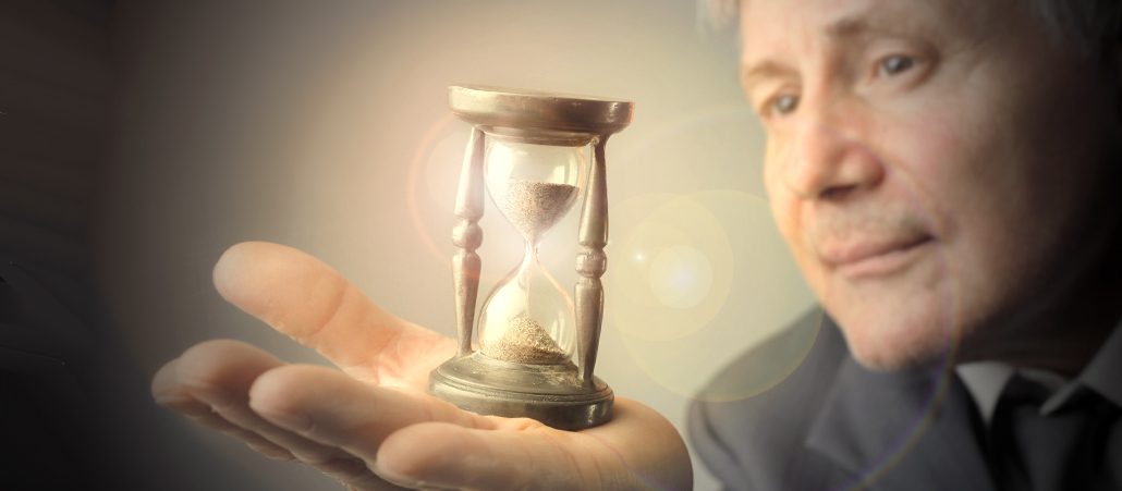 Älterer Mann balanciert Sanduhr auf der Hand. Mystisches Bild.