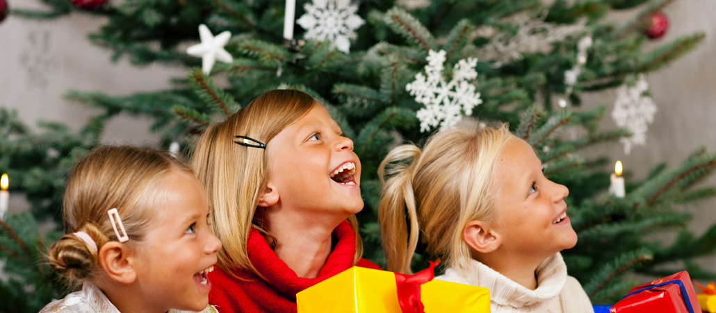 Drei Mädchen mit Geschenken für dem Weihnachtsbaum