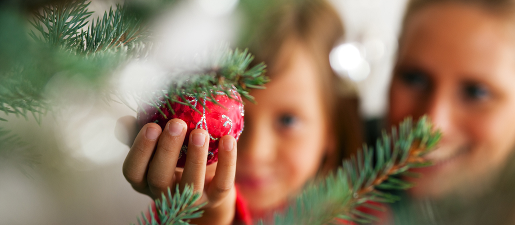 Mutter, Kind (unscharf) schmücken Christbaum mit Kugel