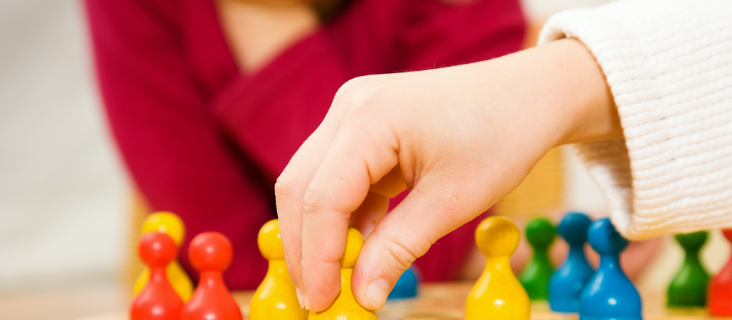 Ein Kind bewegt eine Spielfigur auf einem Brettspiel.