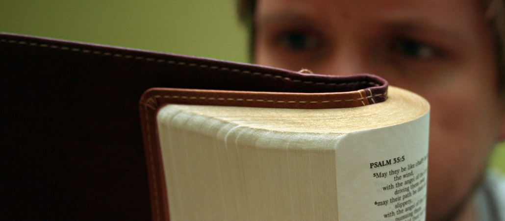 EIn junger Mann liest Psalmen in der Bibel.