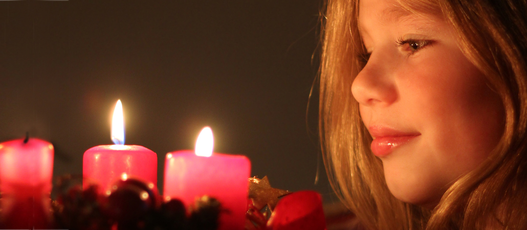 Ein Mädchen schaut auf einen Adventskranz