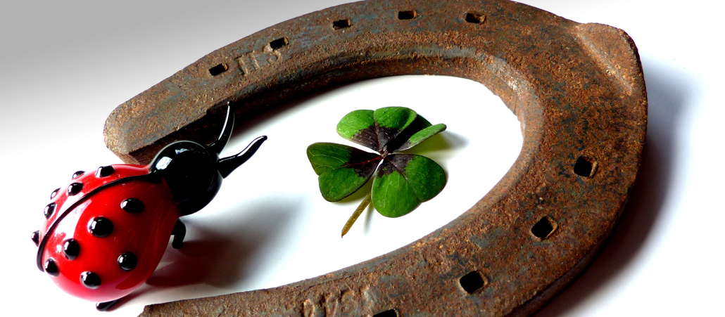 Die Glücksbringer Marienkäfer, ein vierblättriges Kleeblatt und ein Hufeisen.