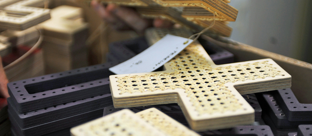 Mehrere Flechtkreuze liegen übereinander auf einem Tisch.