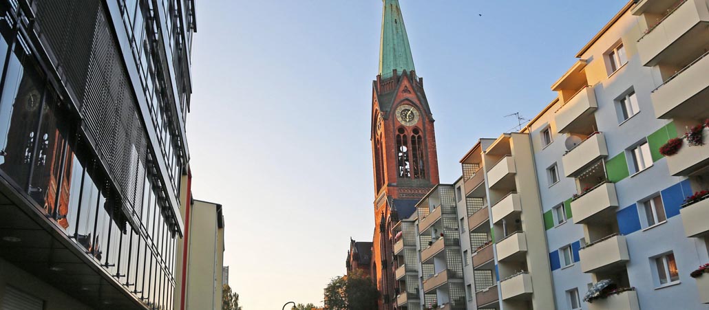 Eine Kirche eingerahmt von Plattenbauten