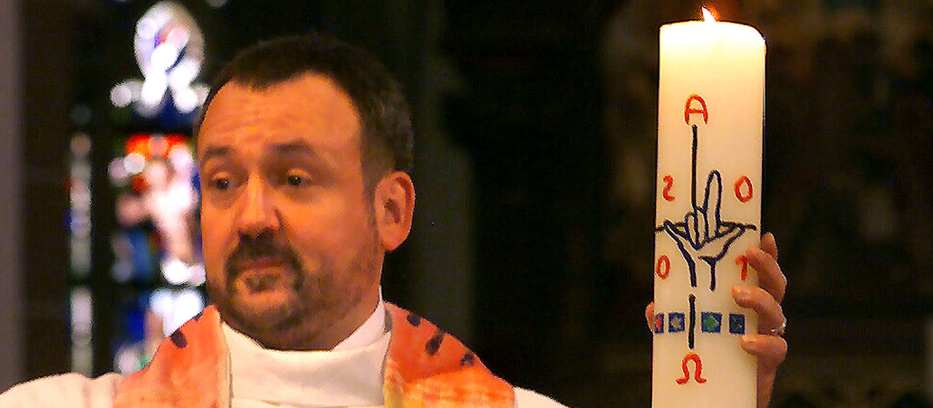 Ein Priester mit einer Osterkerze.