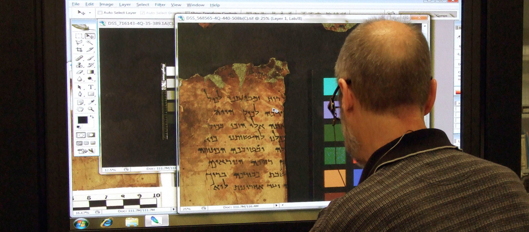 Ein Mann betrachtet auf dem Bildschirm die digitalisierte Form einer Schriftrolle aus den Höhlen von Qumran.