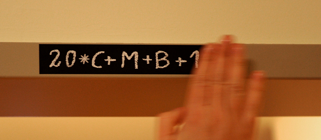 Eine Person klebt das Sternsingerzeichen "C+M+B" auf.