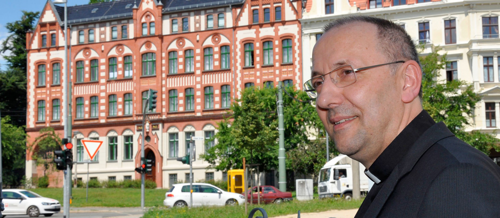 Wolfgang Ipolt, der Bischof von Görlitz steht vor einer Straße und einer Häuserzeile.