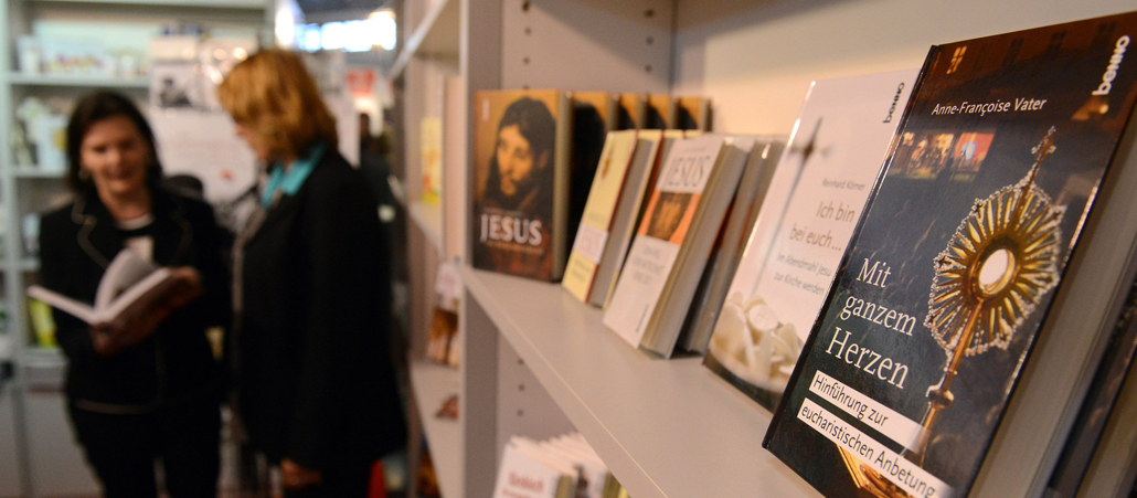 Zwei Frauen unterhalten sich über ein Buch. Im Vordergrund religiöse Bücher