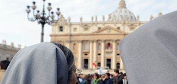 Zwei Ordensfrauen mit Schleier auf dem Petersplatz schauen zum Petersdom.