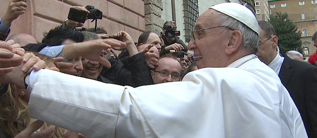 Papst Franziskus (links) begrüßt Gläubige, die ihm die Hand reichen oder ihre Fotoapparate hochhalten.