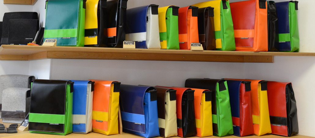 Bunte Taschen stehen in drei übereinanderliegenden Regalfächern.