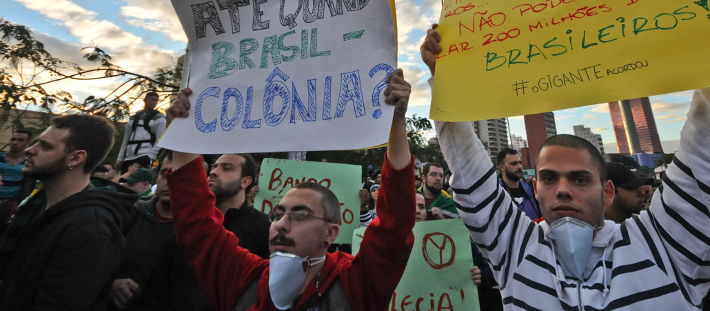 Zwei Brasilianer halten Plakate mit Protestslogans in die Höhe.