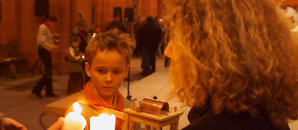 Gottesdienstteilnehmer entzünden Kerzen am Friedenslicht. Bild von 2007.