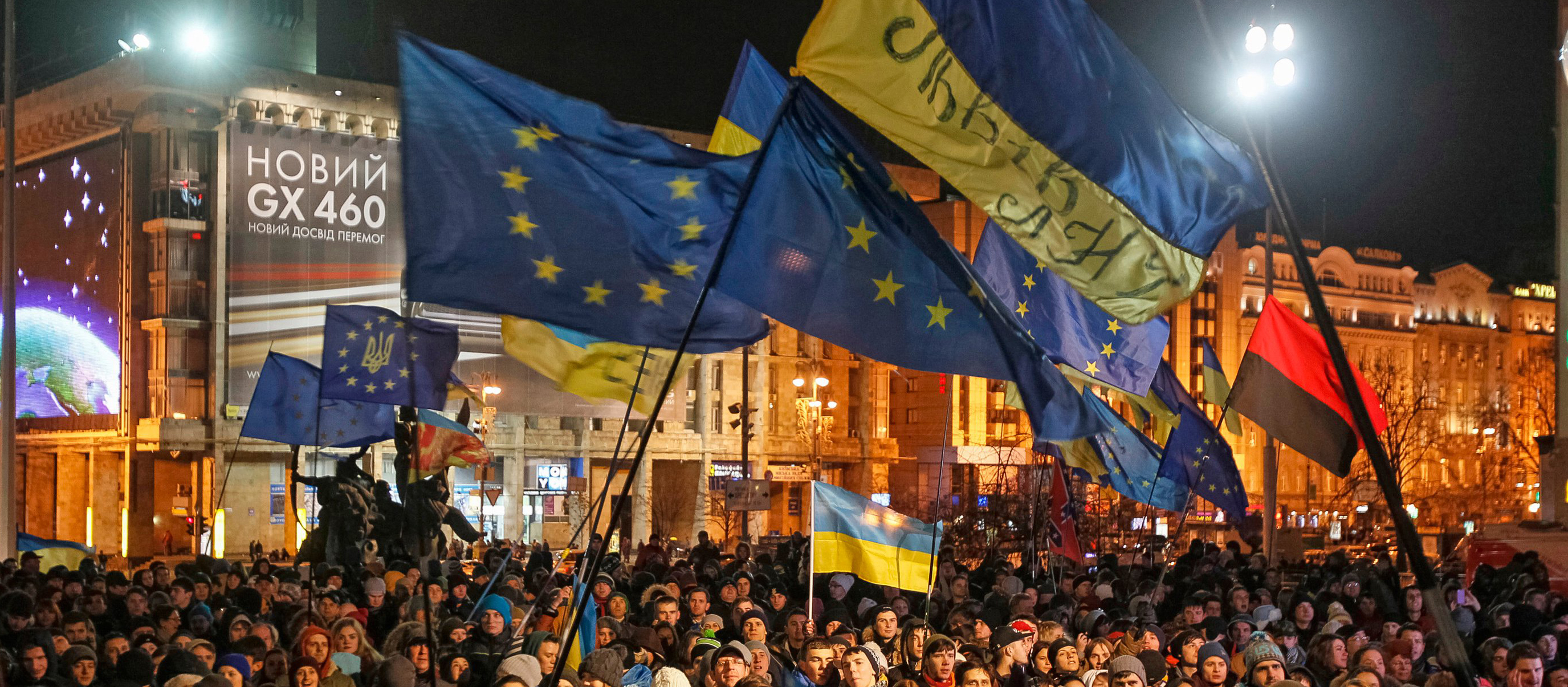 Viele Menschen schwenken große ukrainische und EU-Flaggen in einer kalten Nacht in Kiew.