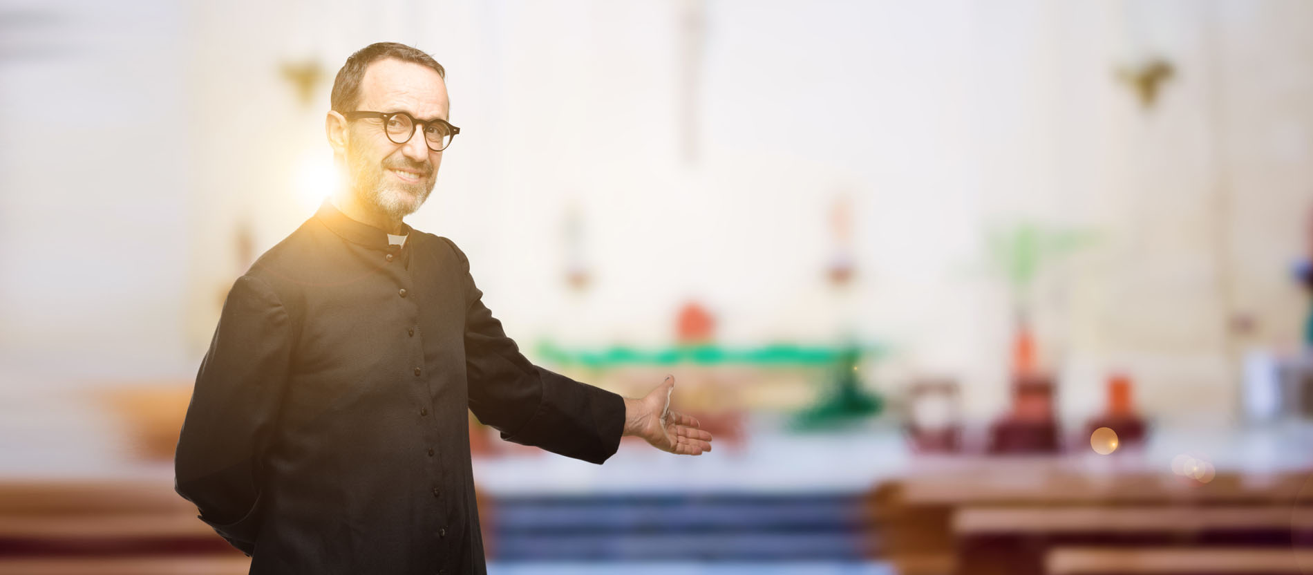 Herzlich willkommen! Ein Priester lädt in die Kirche ein.