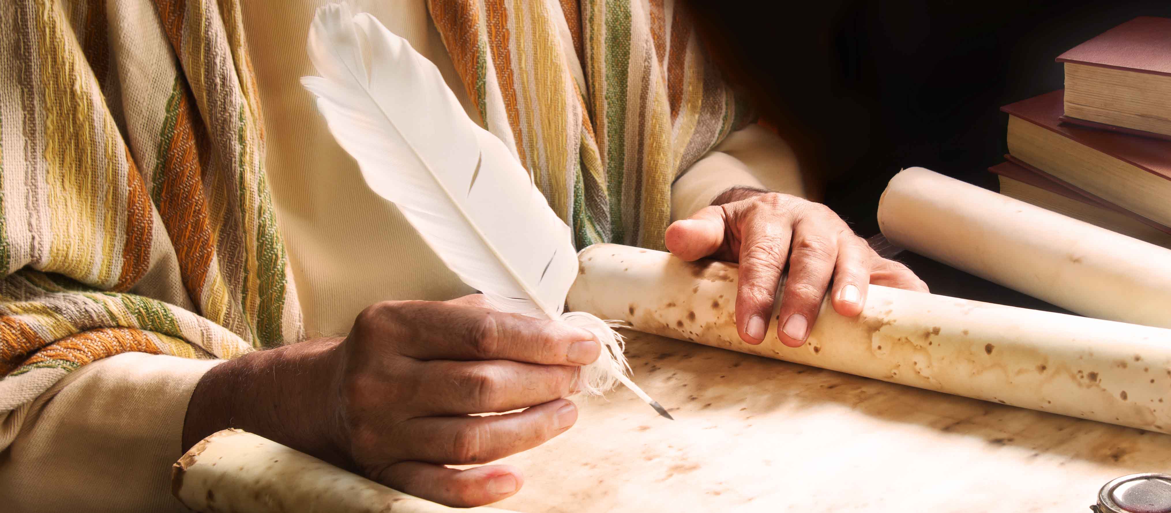 Hand schreibt mit Feder auf Pergament