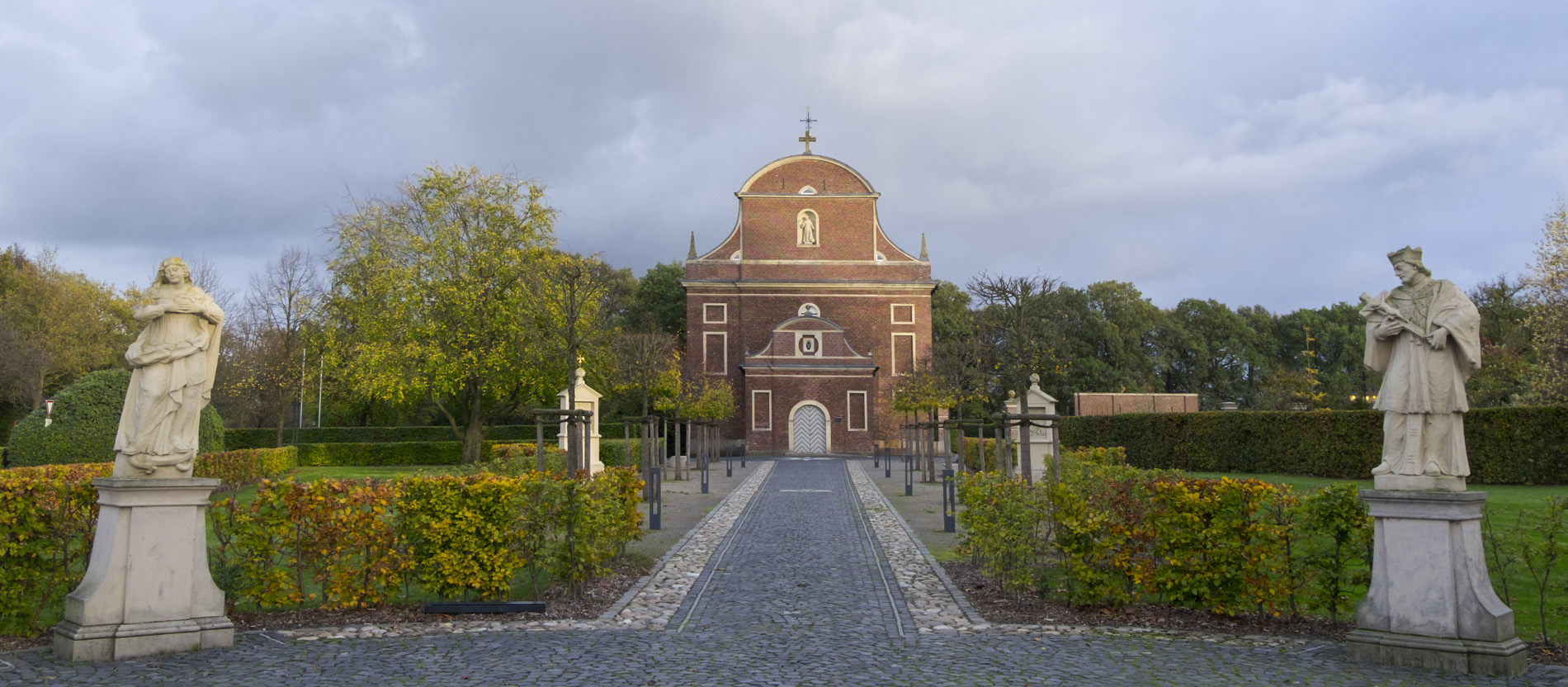 Zwei Heiligenstatuen rahmen den Weg zur Barockkirche St. Franziskus in Zwillbrock.