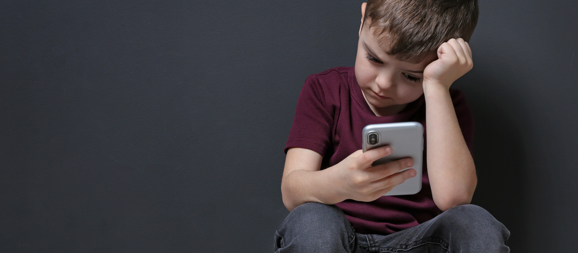 Ein Kind schaut traurig auf sein Smartphone. 