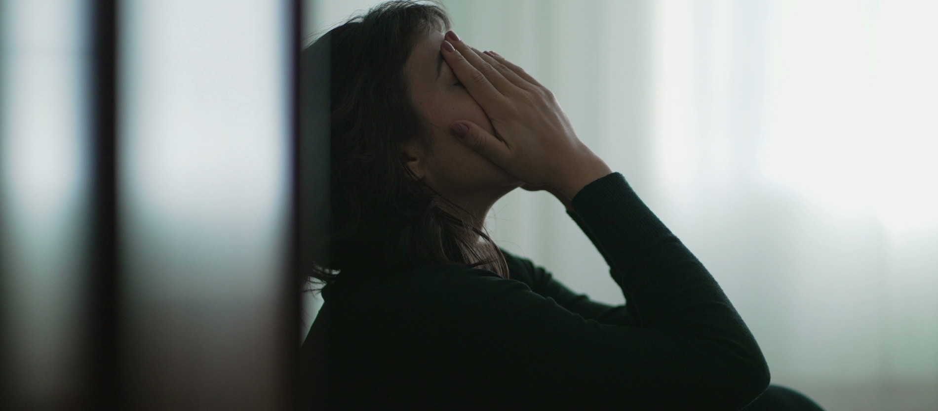 Eine Frau sitzt auf dem Boden und bedeckt verzweifelt ihr Gesicht mit den Händen 