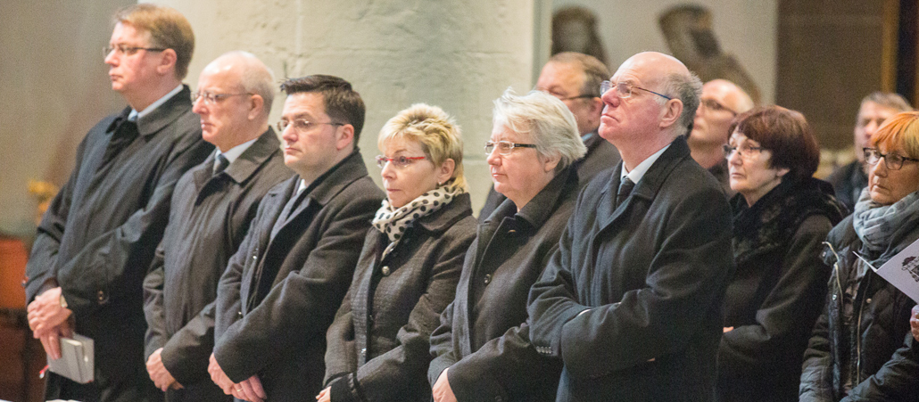 Schwarz gekleidete Menschen in einer Kirchenbank