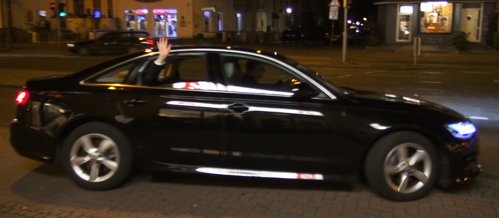 Bischof Bode winkt aus einem anfahrenden Auto heraus