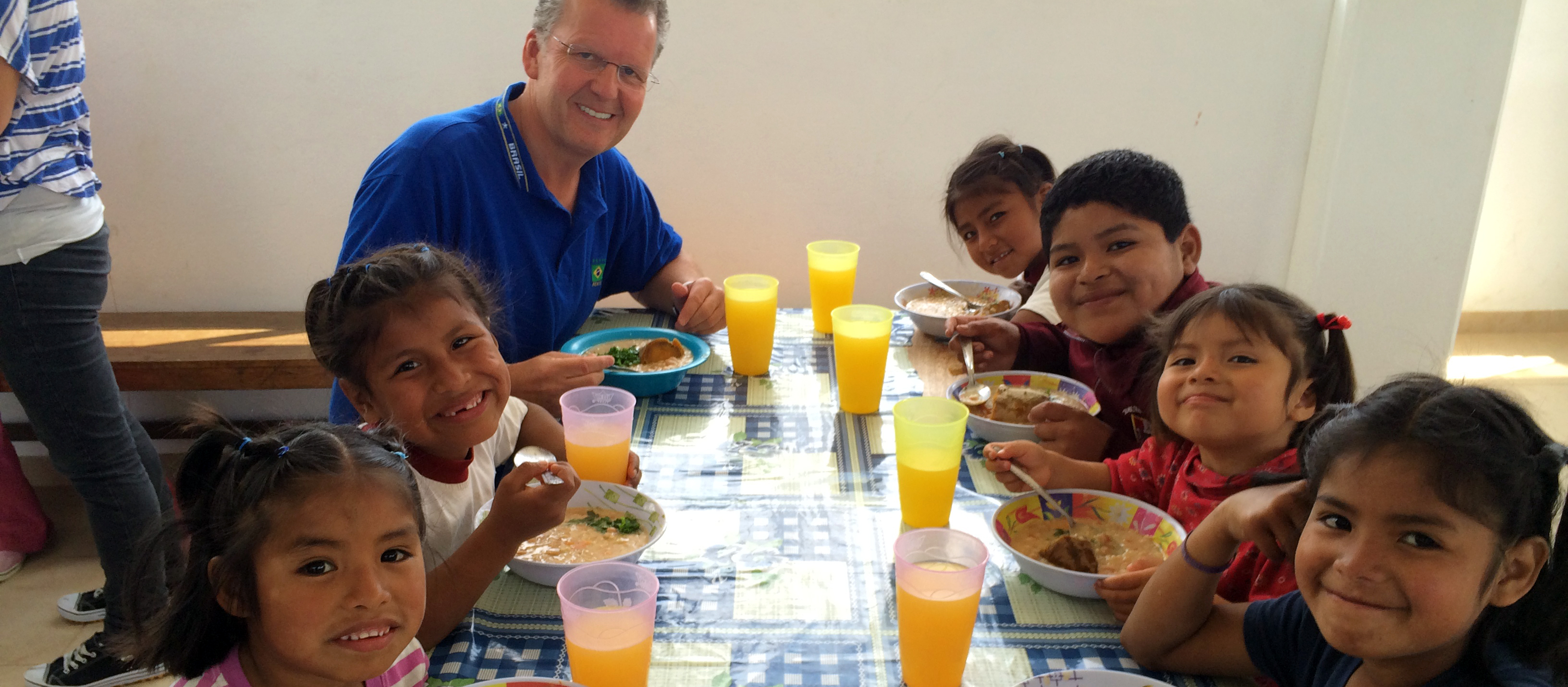Walter Brüggemann sitzt mit Kindern an einem Tisch.