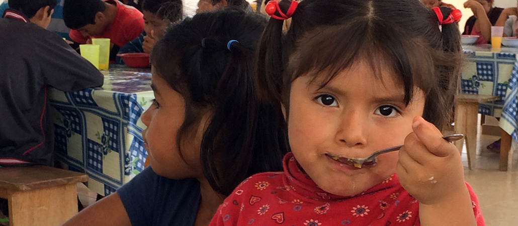 Ein Mädchen nimmt einen Löffel mit Essen in den Mund.