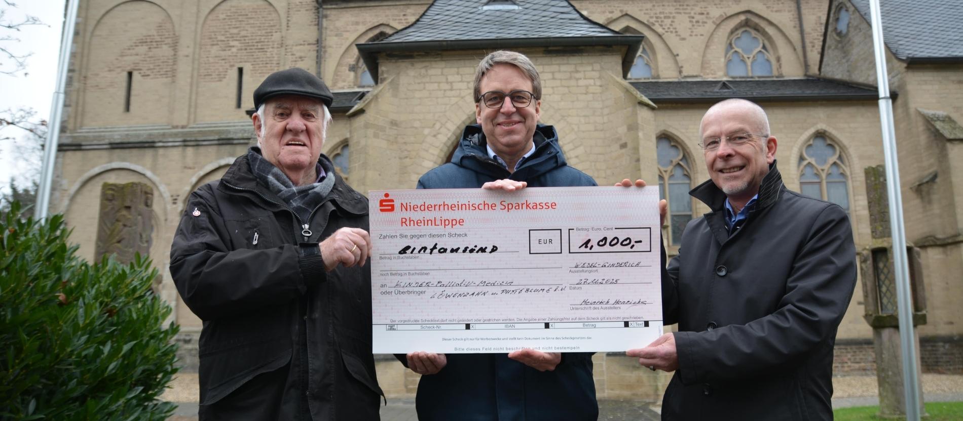 Henrichs (l.) übergab den Scheck zusammen mit Pfarrer Dietmar Heshe (r.) an Ralf Berensmeier, Vorsitzender des Fördervereins Kinderpalliativmedizin Löwenzahn und Pusteblume.