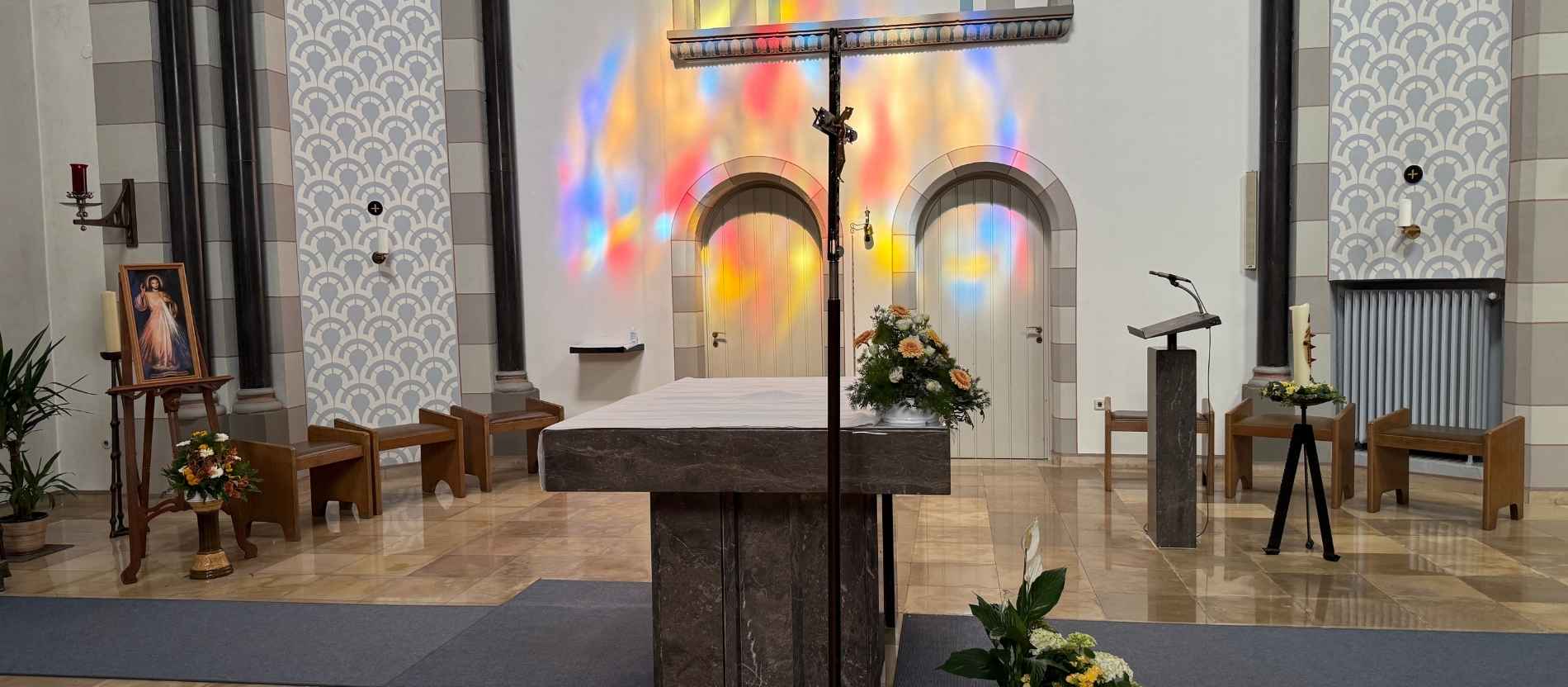 Die Klosterkirche des Kloster Kreitz in Neuss mit Altar und Sedilien. Im Hintergrund bricht sich das Sonnenlicht durch die Bleiglasfenster.