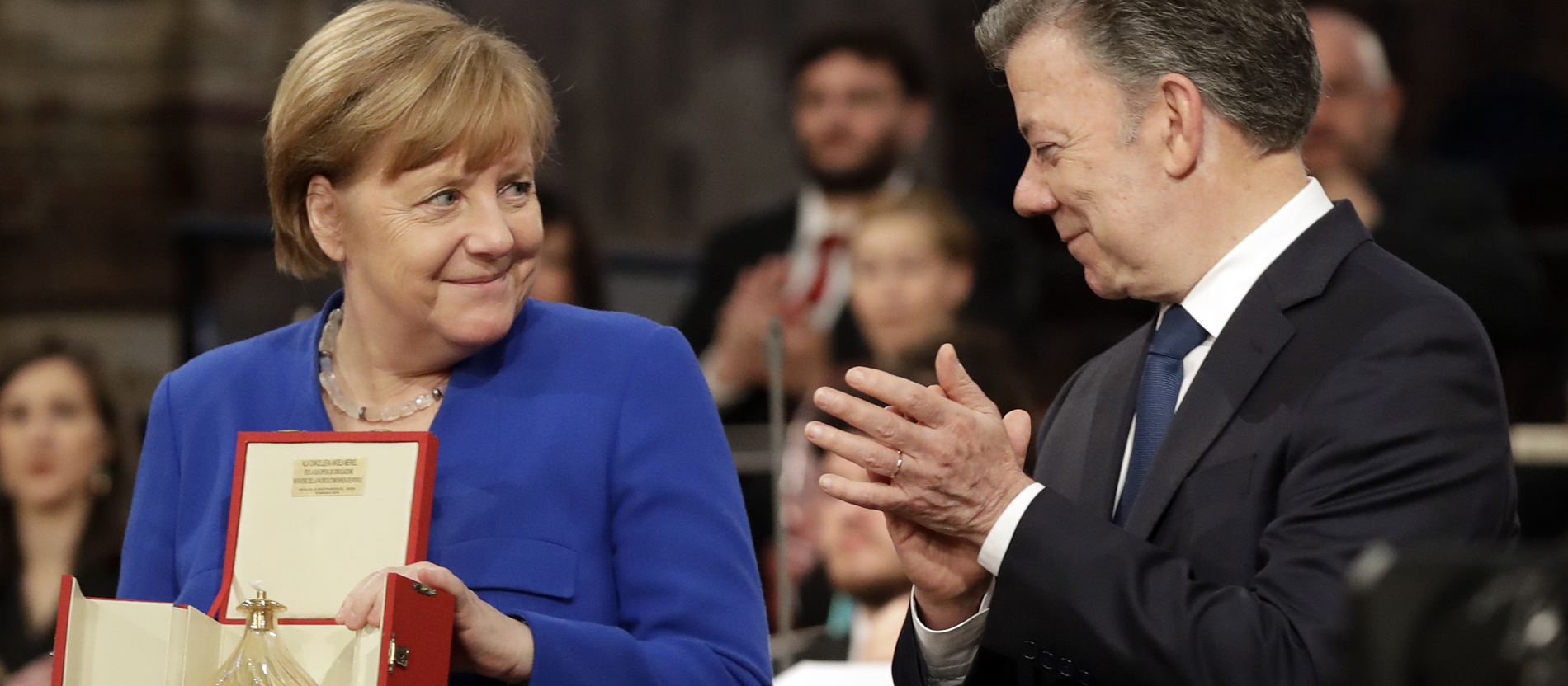 Bundeskanzlerin Angela Merkel nimmt in Assisi von Kolumbiens Präsident Juan Manuel Santos das Friedenslicht der Franziskaner entgegen.