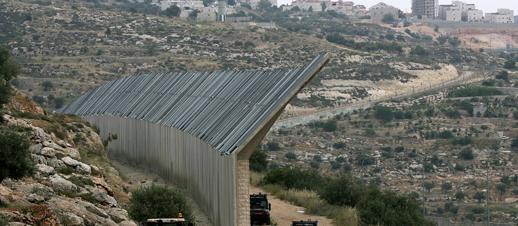 Eine Mauer wird in die Landschaft gebaut.