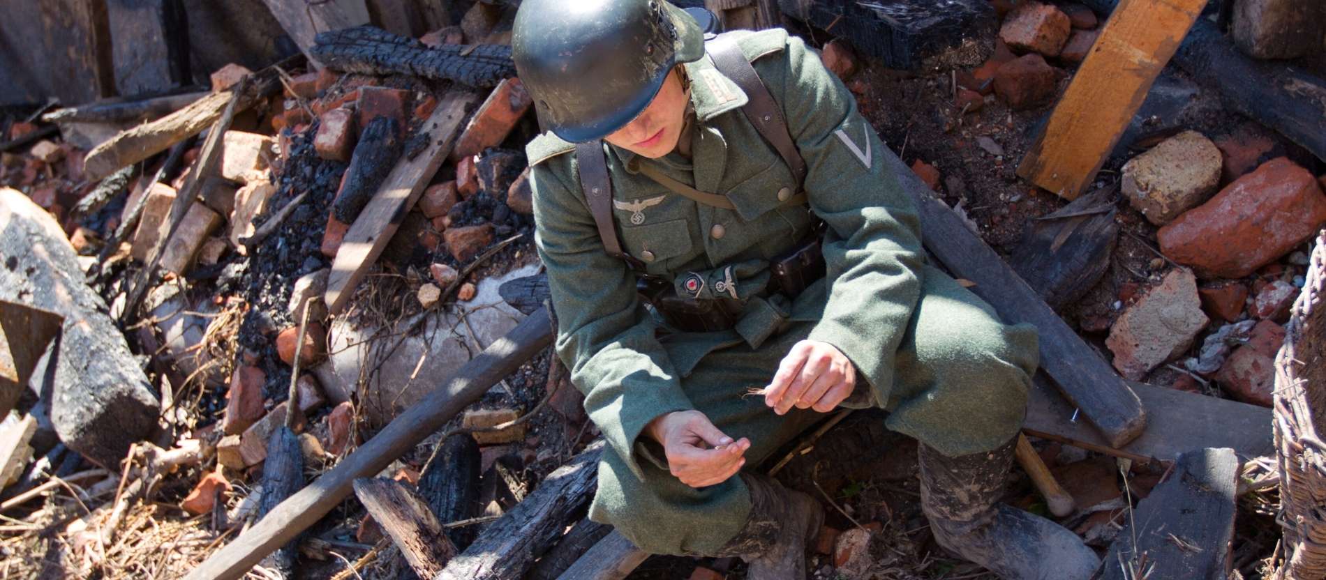 Ein Schauspieler sitzt in Trümmern. Er spielt einen Wehrmachtssoldaten. 