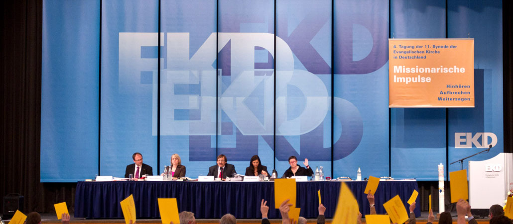 Ein Podium vor einem blauen Hintergrund mit der Aufschrift EKD