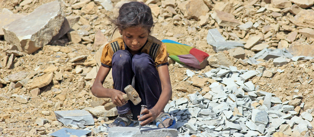 Die etwa 8-jährige Sunita sitzt in Kota, in der indischen Provinz Rajasthan, in einem Steinbruch und arbeitet mit Hammer und Meißel.