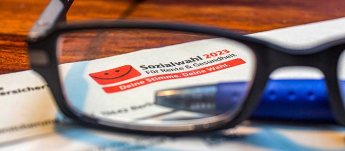 Wahlunterlagen für die Sozialwahl 2023 liegen auf einem Tisch.