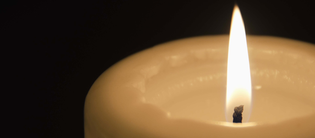 Die weiße Kerze leuchtet in der Dunkelheit.