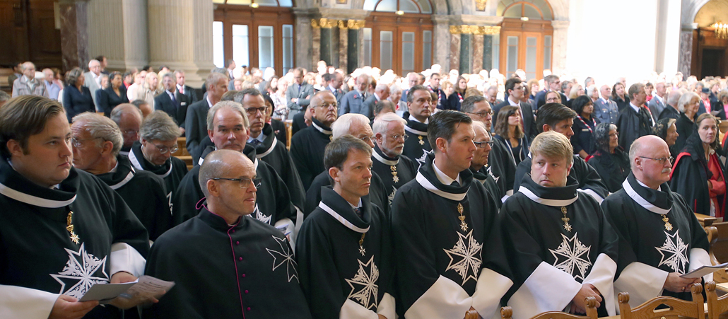 Hunderte Johanniter und Malteser sitzen in Uniform im Berliner Dom