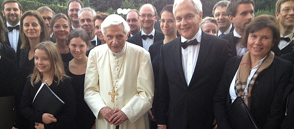 Benedikt XVI. steht neben Chorleiter Rainer Schütz. Beide sind eingeramht von den Sängerinnen und Sänger der 