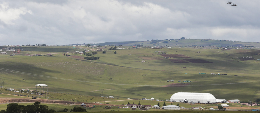 Ein hügelige, früne Landschaft mit einem weißen Zelt