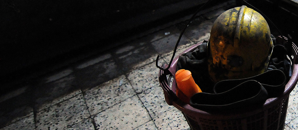 Ein Eimer mit einem Helm hängt in einem rußverschmierten Raum.