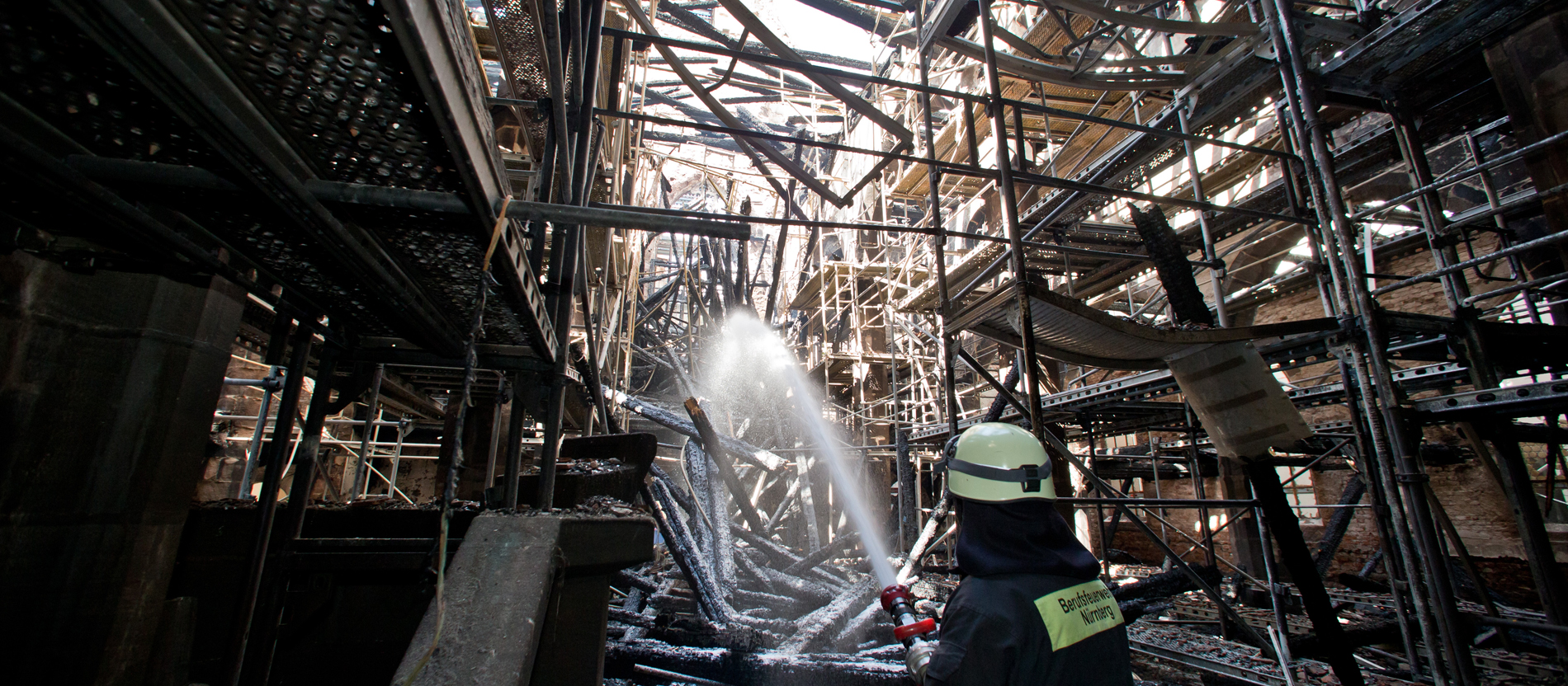 Ein Feuerwehrmann löscht in der durch einen Brand zerstörte Kirche St. Martha