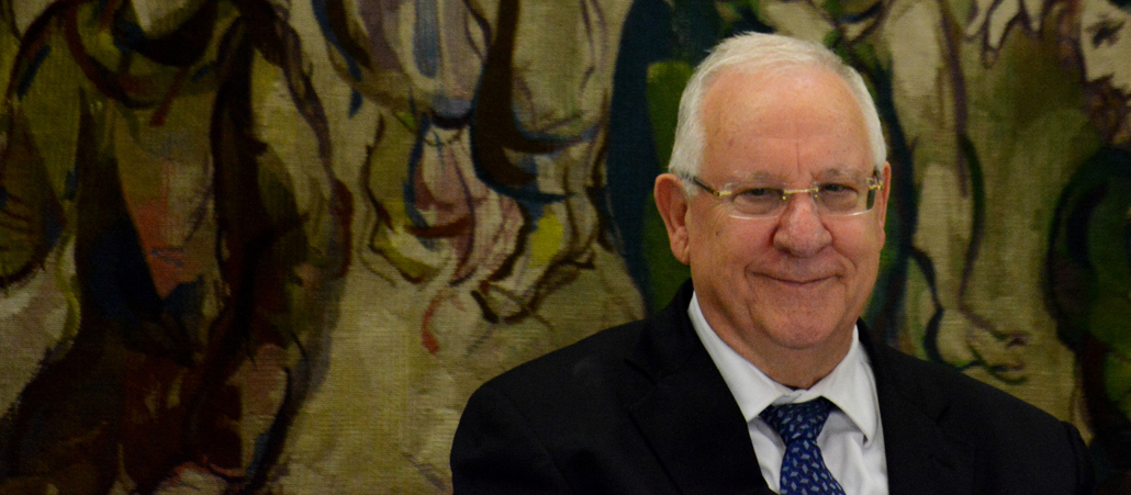 Ein älterer Mann steht vor einem Wandteppich in der Knesset.
