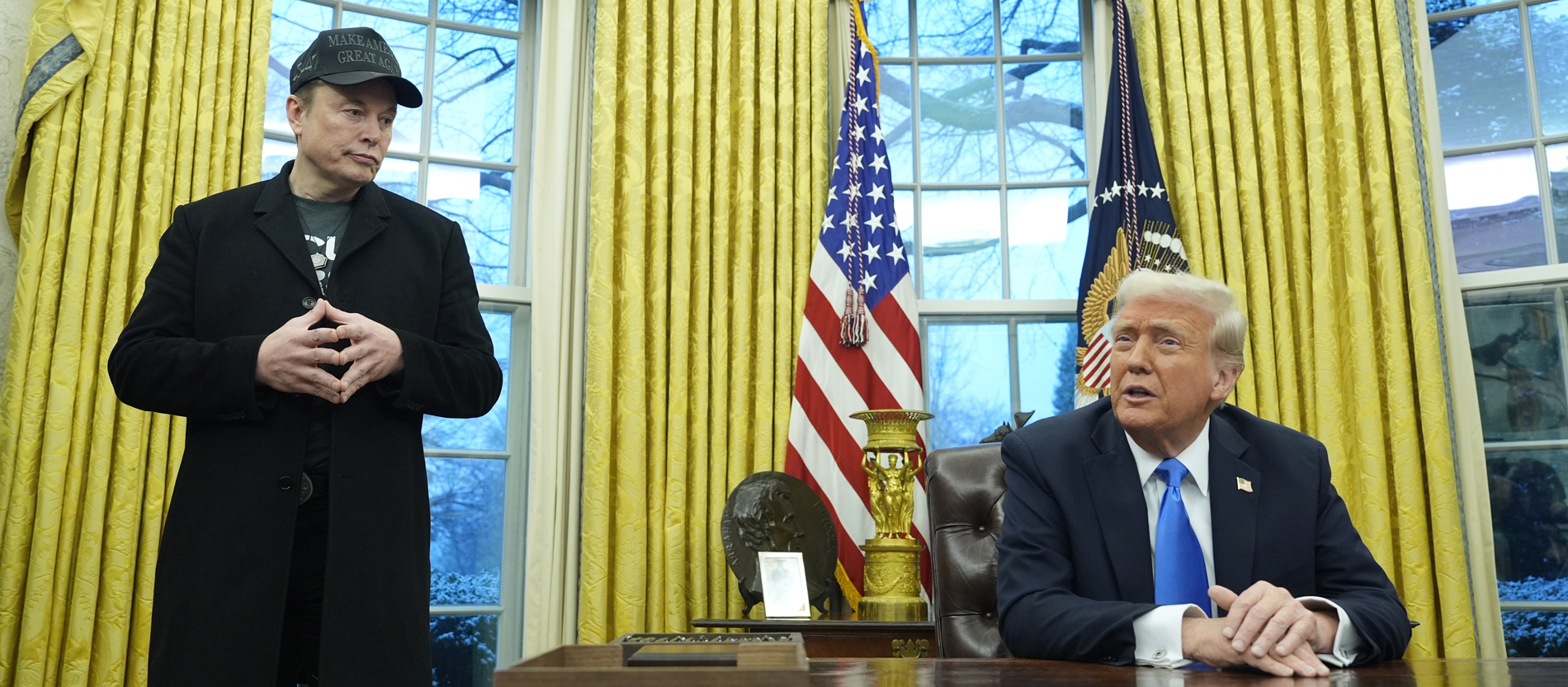 Elon Musk und Donald Trump an einem Schreibtisch im Oval Office