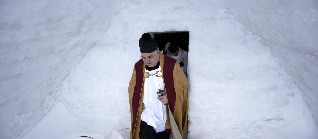 Ein Priester verlässt eine Kirche, die komplett aus Eisblocks und Schnee gebaut ist.