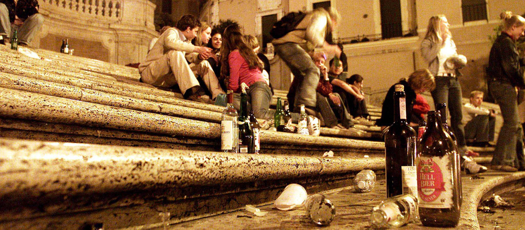 Junge Menschen sitzen auf der Spanischen Treppe in Rom und trinken Bier.