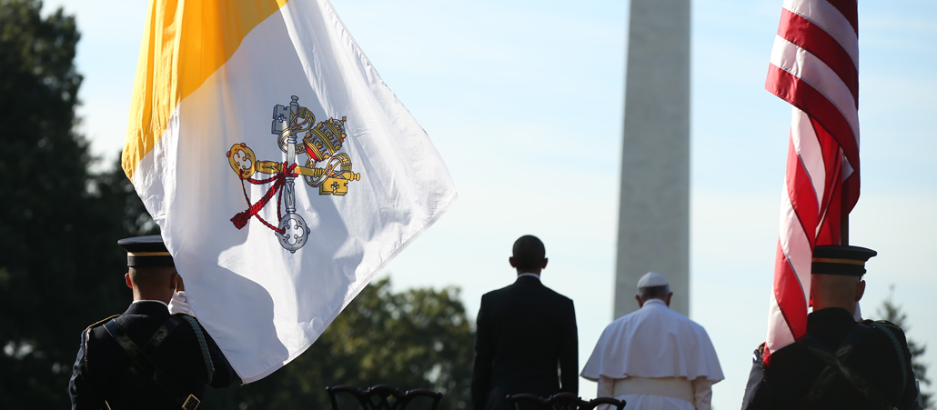 US-Präsident Barack Obama und Papst Franziskus zwischen einer Flagge des Vatikan und einer Flagge der USA.