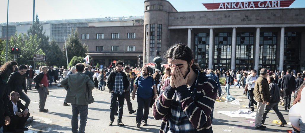Ein junger Mann steht fassungslos vor dem Bahnhof von Ankara, wo sich kurz zuvor ein Terroranschlag ereignet hatte.