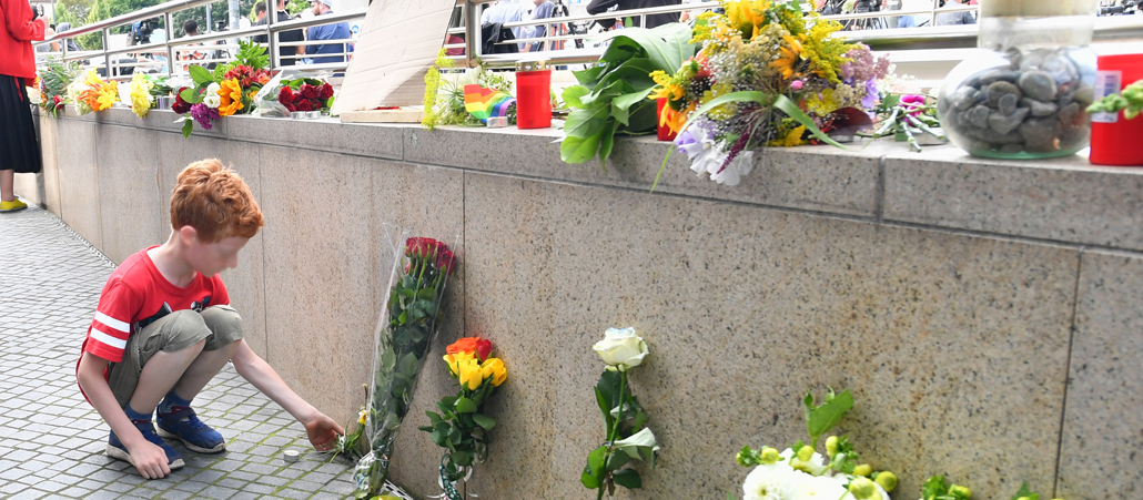 Ein junge legt Blumen am Tatort des Amoklaufs in München nieder.